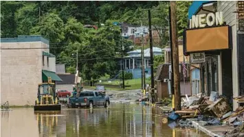  ?? JON CHERRY/THE NEW YORK TIMES ?? Workers clear debris from a flooded street Monday in Fleming-Neon, Kentucky.