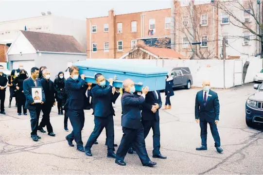  ?? JUSTIN J. WEE/PHOTOS BY THE NEW YORK TIMES ?? Yang Gao holds a photo of his mother as her coffin is carried from a funeral home in New York City. He and his father will take her ashes to China.