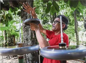 ??  ?? Perfecting the spin: Ismail spinning his tops in order to test their balance at his home in Kampung Padang Bemban, Kelantan. — Bernama
