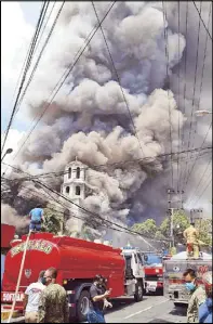  ?? RUSSELL PALMA, MEL ELONA ?? Firefighte­rs inspect the razed Sto. Niño Parish church in Pandacan, Manila yesterday. Above, smoke billows from the church during the fire that also destroyed an adjacent convent. The church housed centuries-old religious icons, among them the 300-year-old wooden image of the Sto. Niño de Pandacan.