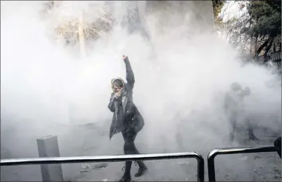  ?? AP PHOTO ?? In this Saturday, Dec. 30, 2017, photo taken by an individual not employed by the Associated Press and obtained by the AP outside Iran, a university student attends a protest inside Tehran University while a smoke grenade is thrown by anti-riot Iranian...