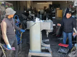  ?? (AP/Terry Chea) ?? Jose Bonilla Jr. (right) talks to an employee in January about cleaning a used industrial mixer for sale at the warehouse of his family’s business, American Restaurant Supply in San Leandro, Calif.