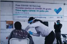  ?? JEFF CHIU — THE ASSOCIATED PRESS ?? A National Guard member, center, administer­s a COVID-19 vaccine to a farmworker at a Santa Clara County mobile vaccinatio­n clinic at a Monterey Mushrooms facility in Morgan Hill on March 3.