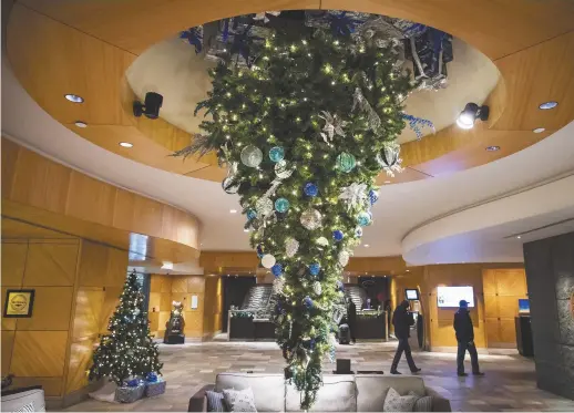  ??  ?? D’une taille de 2,75 mètres, le sapin de Noël de l’hôtel Fairmont de l’aéroport de Vancouver est suspendu à l’envers dans le hall d’entrée. - La Presse canadienne: Darryl Dyck