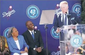  ?? Victor Decolongon/Getty Images ?? Rachel Robinson, left, widow of Jackie Robinson, and Kevin Frazier listen to master of ceremonies Vin Scully at the statue unveiling.