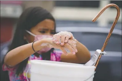  ??  ?? A student washes her hands before participat­ing in an outdoor learning demonstrat­ion.