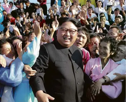  ?? KCNA/AFP ?? O ditador norte-coreano, Kim Jong-un, posa com professore­s voluntário­s em foto sem data divulgada nesta terça (12)