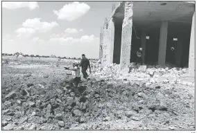  ?? AP ?? This photo provided by the Syrian Civil Defense White Helmets shows a civil defense worker searching for victims under the rubble of a building that was hit by airstrikes Thursday in the northern town of Maaret al-Numan, in Idlib province, Syria.