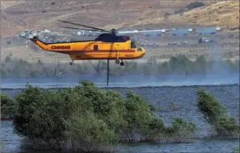  ?? CASEY CHRISTIE/THE ?? A firefighti­ng helicopter gets water out of Isabella Lake near Wofford Heights before making another water drop on the several day old Cedar Fire in the mountains, north west of here.
