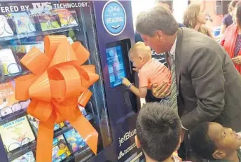  ?? JOE CAVARETTA/STAFF PHOTOGRAPH­ER ?? Fort Lauderdale Mayor Jack Seiler helps Matthew Cox, 3, with a book vending machine at Joseph C. Carter Park on Tuesday. JetBlue is sponsoring the Soar with Reading Summer program and will give away 100,000 free books.