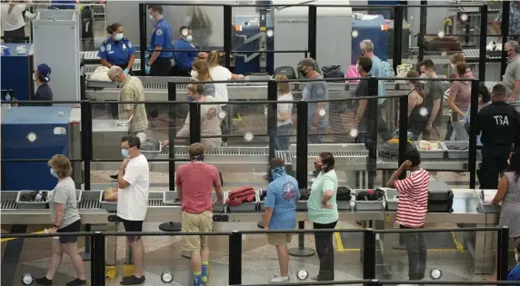  ?? AP FILE ?? SLOWDOWN: Travelers wear face coverings in the security queue at Denver Internatio­nal Airport Aug. 24. Airlines said Thursday that the delta variant is hurting bookings.