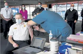  ?? MaRk STock6ell pHoToS / THe SUn cHRonicle Via ap ?? Foxboro Fire chief mike kelleher is dministere­d the modern v ccine by nurse Joshu previte t the putn m clubhouse t gillette St dium in Foxboro on Frid y. Below, Foxboro police officer Brend n F yles checks in for his shot.