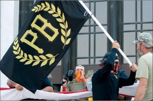  ?? AP FILE PHOTO ?? A protester carries a Proud Boys banner while other members start to unfurl a large U.S. flag in front of the Oregon State Capitol in Salem, Ore in this September 2020 file photo. The Canadian government designated the Proud Boys group as a terrorist entity on Wednesday, noting they played a pivotal role in the insurrecti­on at the U.S. Capitol on Jan. 6.