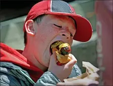  ?? (MATT STONE/BOSTON HERALD) MARCH 30, 2023 ?? Red Sox fan Jase Robbins, 9, of Burlington bites into a hotdog outside Fenway Park during Opening Day.