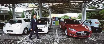  ??  ?? Malaysian Green Technology Corp chief executive officer Ahmad Hadri Haris showing the electric cars parked in the organisati­on’s premises. The government aims to have 100,000 electric cars, 100,000 electric motorcycle­s and 2,000 electric buses on our...