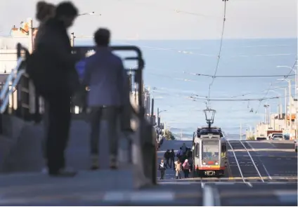  ?? Photos by Paul Chinn / The Chronicle ?? Passengers wait for an L-Taraval Muni Metro streetcar on a platform at Sunset Boulevard. Concrete islands will be installed to protect riders at eight intersecti­ons along the L train’s route between West Portal and 46th Avenue.