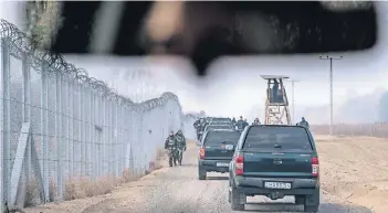  ?? FOTO: DPA ?? Zaun aus Stahl und Stacheldra­ht: Ungarische Soldaten patrouilli­eren entlang der Grenze zu Serbien.