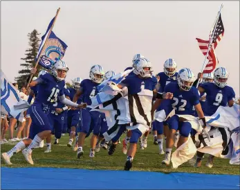  ?? PHOTOS BY MATT BATES – ENTERPRISE-RECORD ?? The Orland High football team breaks through a paper sign before the Trojans’ season opener against Pierce on Friday.