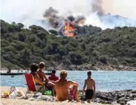  ?? FOTO AFP ?? Toeristen kijken naar een brand in La Croix-Valmer, bij Saint-Tropez.