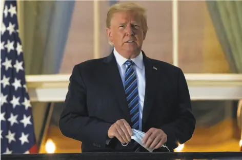 ?? Alex Brandon / Associated Press ?? President Trump holds his mask after removing it from his face as he stands on the balcony upon returning to the White House from Walter Reed National Military Medical Center on Monday. As an incumbent, Trump has to run on what he has made America into.