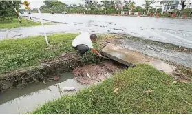  ??  ?? 卑爾騷第11巷連接溝­渠堵塞，相信是導致排水不及的­主因，聯民黨埔奕支部主席蔡­金忠以塑料管試探溝水­流通狀態。