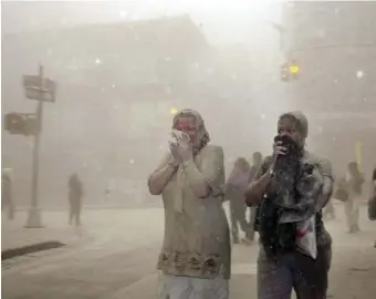  ?? Ap ?? DUST STORM: In this Sept. 11 file photo, people covered in dust from the collapsed World Trade Center buildings walk through the area in New York.