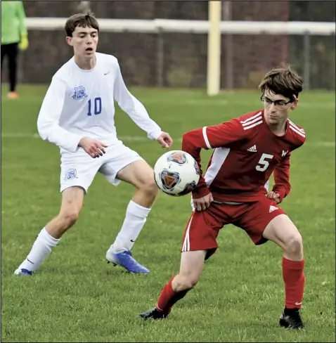  ??  ?? Dylan Whitehead of Wapakoneta keeps his eyes on the ball during Monday’s sectional playoff game against Defiance. Shown for the Bulldogs is Andrew Frederick.
Photo by John Zwez