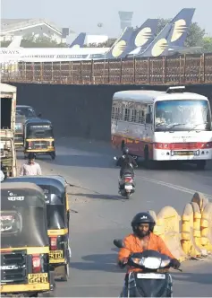  ?? — AFP photo ?? Vehicles ply along a road adajacent to Jet Airways aircraft parked at the airport in Mumbai on April 10. The Mumbai-based carrier has been forced to ground the majority of its fleet after months of defaulting on loans and struggling to pay lessors and staff.