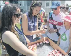  ?? MITCH MACDONALD/THE GUARDIAN ?? City of Charlottet­own employees, from left, Laurel Lea and Charlotte Nicholson, hand out some Canada Day-themed cupcakes at Victoria Park on Sunday.