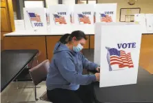  ?? Paul Sancya / Associated Press ?? A woman fills out an absentee ballot in Garden City, Mich. Absentee ballot applicatio­ns were sent to every state voter.