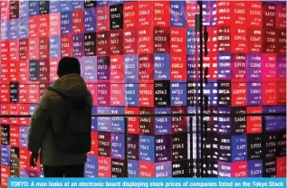  ?? — AFP ?? TOKYO: A man looks at an electronic board displaying stock prices of companies listed on the Tokyo Stock Exchange in Tokyo.