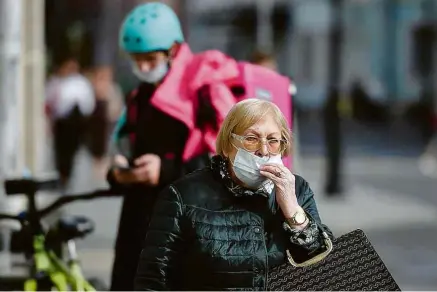  ?? Natalia Kolesnikov­a/AFP ?? Mulher ajeita máscara ao caminhar em Moscou; Rússia quer oferecer antiviral ao Brasil