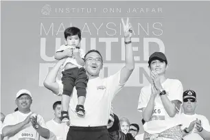  ?? — Gambar Bernama ?? LARIAN AMAL: Hishammudd­in mendukung cucunya ketika hadir bersama isterinya Marsilla (kanan) untuk menyertai larian amal Malaysian United Run di Padang Merbok, Kuala Lumpur, semalam.