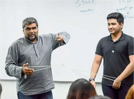  ??  ?? Kumar Nagalingam (left), chief operating officer of BAC’s Skills Academy, challengin­g students with a puzzle during orientatio­n week.