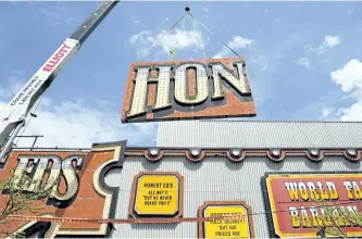  ?? CHRIS YOUNG/THE CANADIAN PRESS ?? Workers remove part of the iconic sign from the shuttered Honest Ed’s department store in Toronto on Tuesday.