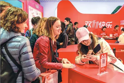  ?? WU JIANDE / FOR CHINA DAILY ?? Visitors are drawn to a promotiona­l event for the Singles Day shopping festival in Shanghai.