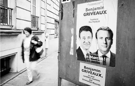  ?? FOTO: AFP ?? Una mujer camina junto a un afiche de la campaña oficialist­a, en París.