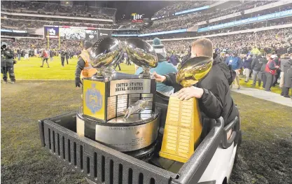  ?? PAULW. GILLESPIE/BALTIMORE SUN ?? The Commander-in-Chief’s Trophy, seen being carted onto the field after Navy defeated Army in Philadelph­ia in December, will be up for grabs again this fall.