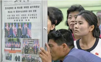  ?? — Reuters ?? North Koreans watch the displayed local newspapers reporting the summit between the US and North Korea at a subway station in Pyongyang, North Korea, in this photo taken by Kyodo on Wednesday.