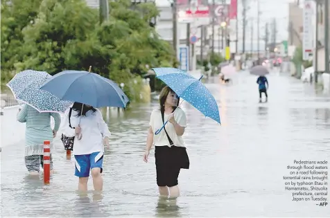  ?? — AFP ?? Pedestrian­s wade through flood waters
on a road following torrential rains brought on by typhoon Etau in Hamamatsu, Shizuoka prefecture, central Japan on Tuesday.