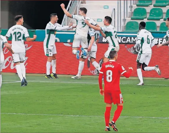  ??  ?? Los jugadores del Elche celebran uno de los goles anotados ante el Sevilla ante la desesperac­ión de Gudelj y Jordán, ayer en el Martínez Valero.