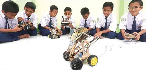  ?? BOY SLAMET/JAWA POS ?? KALI PERTAMA LOMBA: Dari kiri, Ayman Nabil, M. Rayhan Azhar, Rafi Aruna Zaki, M. Alf Jasir, M. Rifqi Anwaruddin, M. Lukman Hakim, dan Azya Dauzy dengan robot karya mereka.