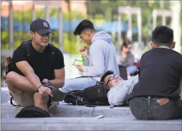  ?? LIPO CHING — STAFF ?? Junior Joey Wang, center, relaxes with friends outside the student union at San Jose State on Wednesday. The survey shows about half of California­ns are skeptical about the value of going to college.