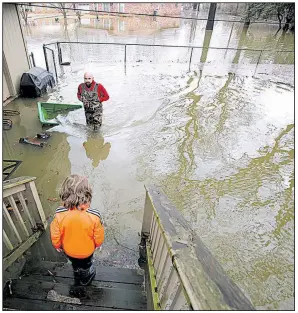  ?? Arkansas Democrat-Gazette/THOMAS METTHE ?? Brett Lukas walks through waist-deep water in his backyard as his son, Brigham, 6, looks on from the deck of their home in Sherwood on Saturday. At least one person was killed Saturday as a strong storm system passed through the state.