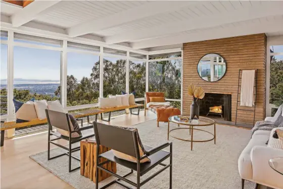  ?? CHRISTIAN KLUGMANN ARCHITECTU­RAL PHOTOGRAPH­Y ?? Above: The living room is warmed by a fireplace and frames views of San Francisco Bay through floor-to-ceiling windows. Below left: Transom and floor-to-ceiling windows welcome natural light into the mid-century Oakland home. Below center: The chef’s kitchen includes a banquette, stainless steel appliances and custom cabinetry. Below right: The deck off the main living level provides an ideal space for outdoor dining.