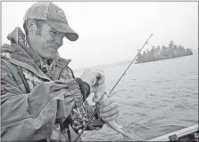  ?? [TONY KENNEDY/MINNEAPOLI­S STAR TRIBUNE] ?? Jeremy Maslowski of Tower, Minn., unhooks a walleye caught on Lake Vermilion while trolling crankbaits with lead core fishing line. The method landed limits of the fish for Maslowski and his fishing partner during a recent cold front when the fish...