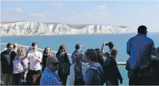  ??  ?? Tourists view the White Cliffs of Dover from a ferry travelling from England to Calais, France.