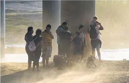  ?? AFP ?? A migrant family from Venezuela stands in a dust storm as they are apprehende­d by US authoritie­s in Eagle Pass, Texas, near the border with Mexico on Thursday.