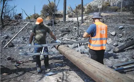  ?? MICHAEL VARAKLAS AP ?? Electric company workers replace a utility pole after a wildfire in the Fyli suburb of Athens, Greece, on Friday. Authoritie­s there are battling a major wildfire that has been described as the European Union’s largest single fire recorded.