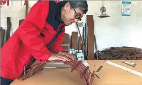  ?? ZHANG WENJING / XINHUA ?? Sun Gang tests the strength of a model wooden-arch bridge he made by putting his weight on it in his workshop in Dingxi, Gansu province.